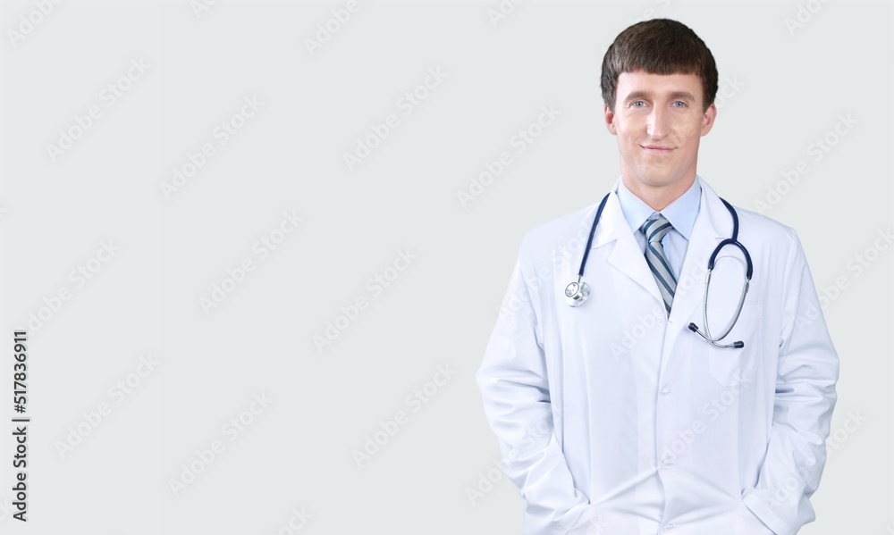 Happy young doctor in a white coat posing