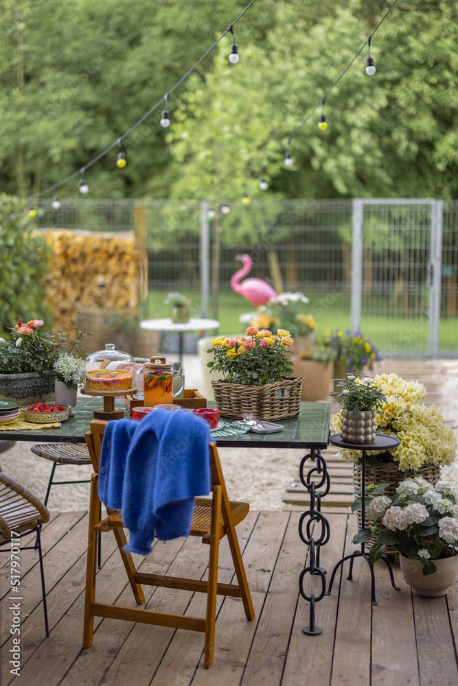 Beautiful backyard with festively served dinner table on a terrace during summer time, wooden chair 