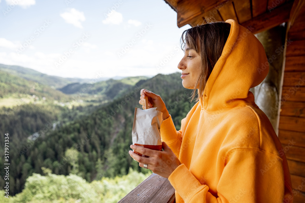 年轻女子用特殊包装吃冻干徒步食品，享受美景