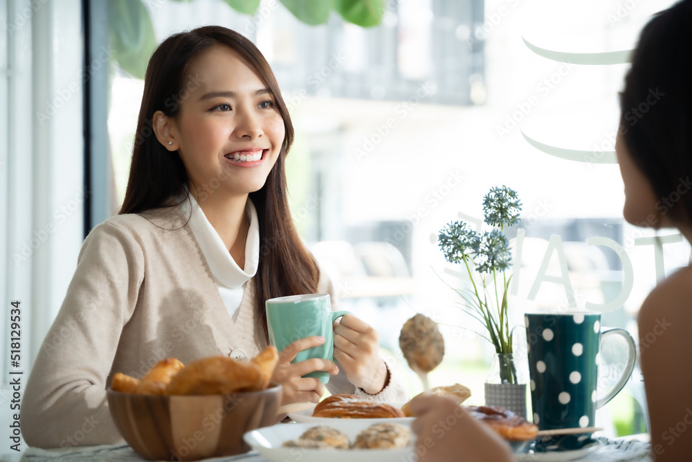 两位年轻的亚洲女性朋友在咖啡店聊天