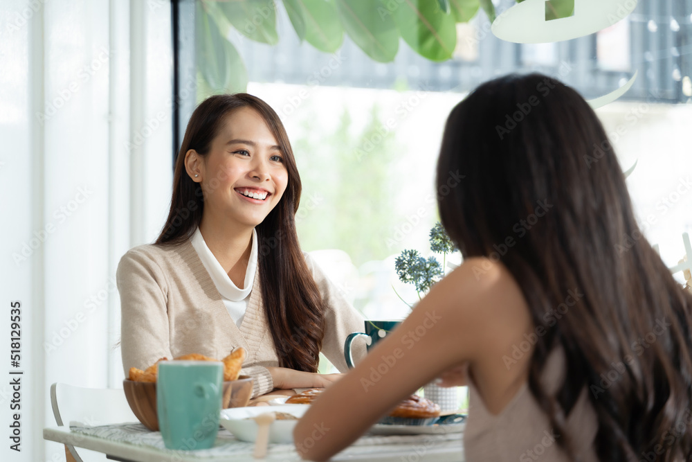 两位年轻的亚洲女性朋友在咖啡店聊天