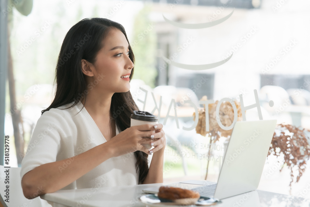 一名亚洲女子在咖啡店使用笔记本电脑，看着外面梦见什么