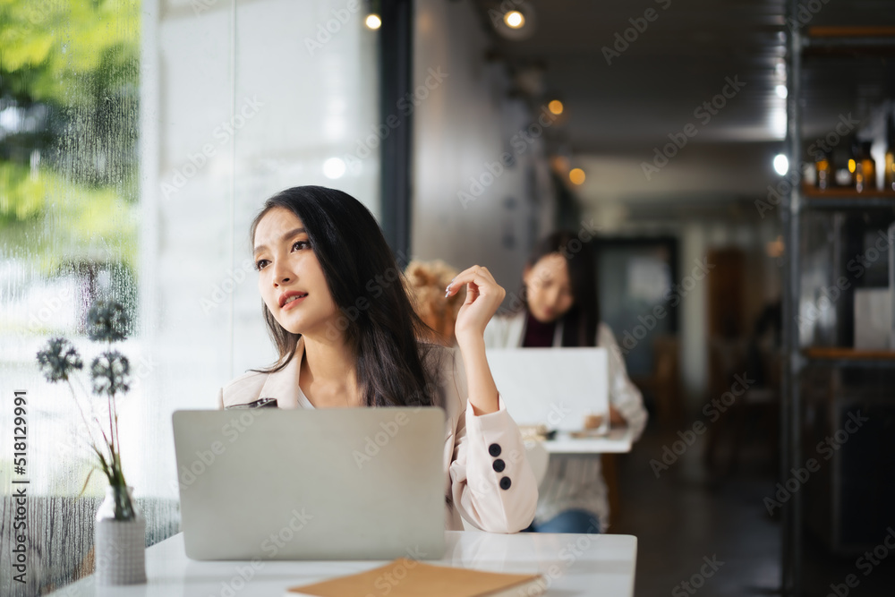 一名亚洲女子在餐厅里使用笔记本电脑，看着外面梦见什么