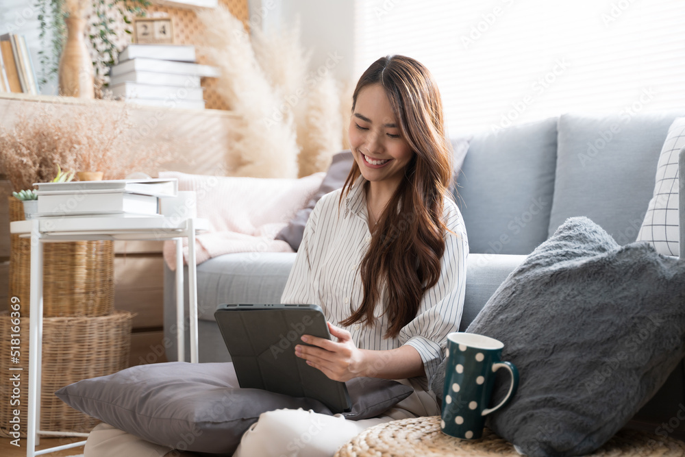 Young Asian woman using tablet living room at home cozy happy working at home.