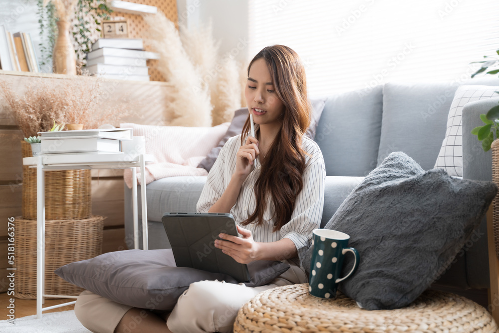 Young Asian woman using tablet and pen in living room