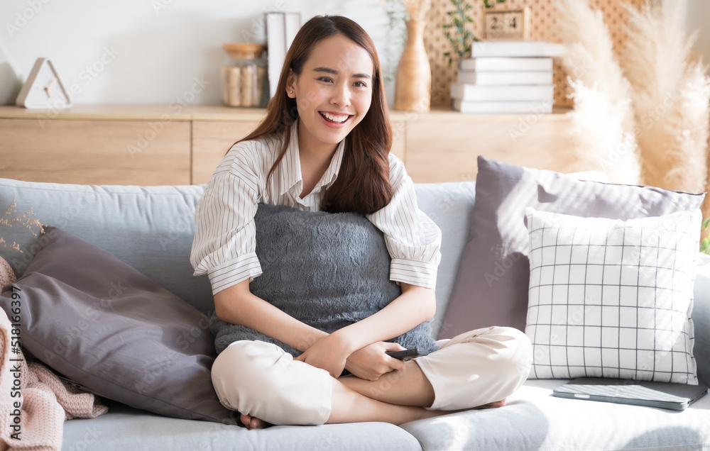 亚洲女人在家的沙发客厅里开心地看电视喜剧连续剧