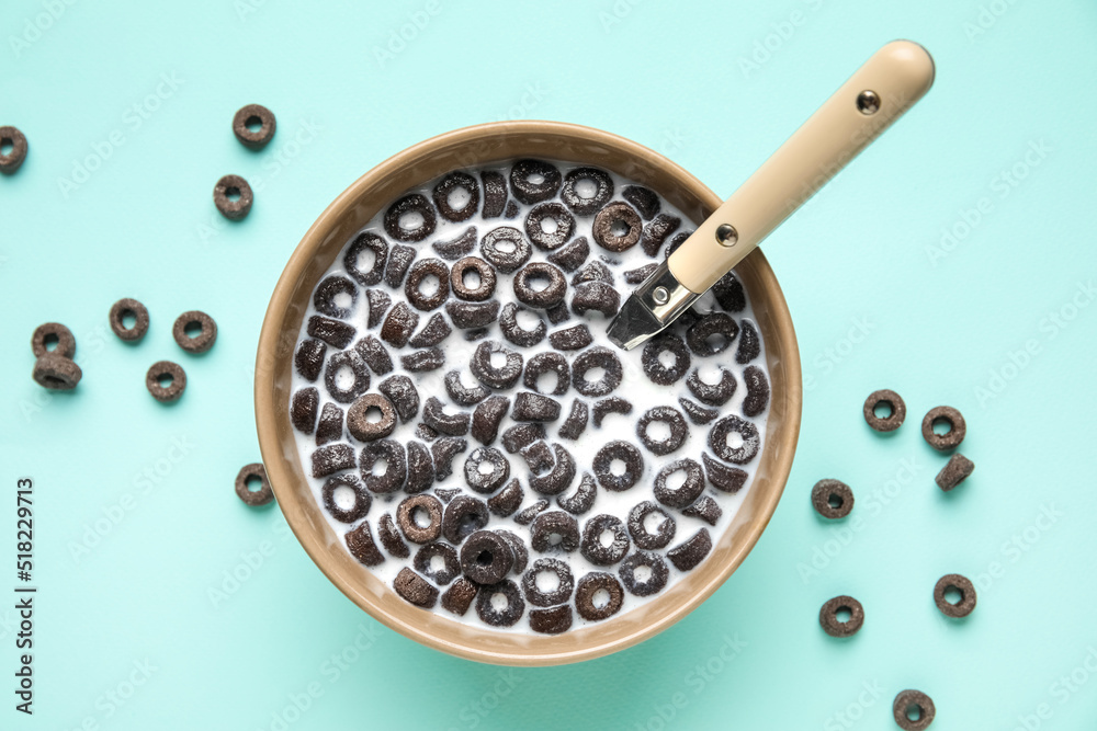 Bowl of tasty cereal rings with milk on color background