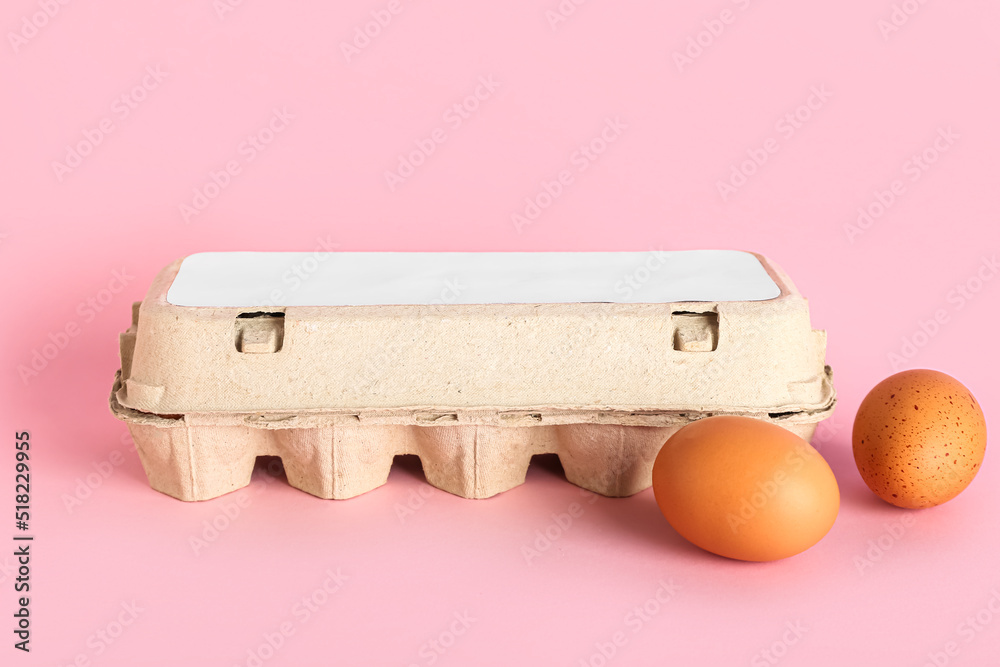 Cardboard holder with brown chicken eggs on pink background