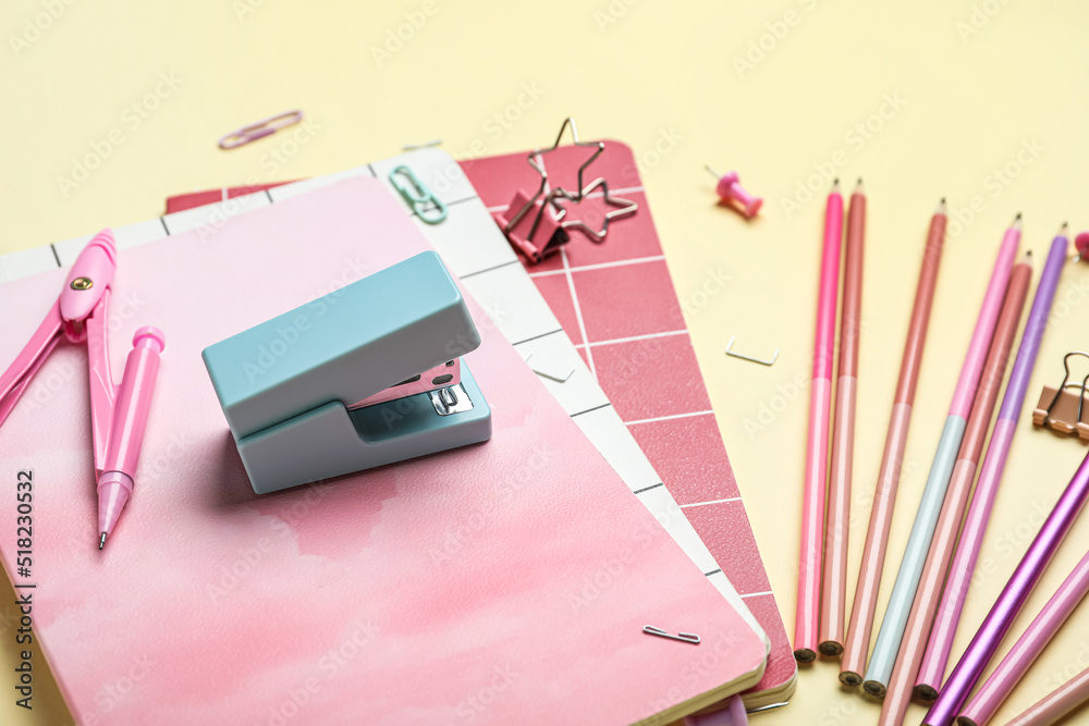 Stapler with different stationery supplies on yellow background