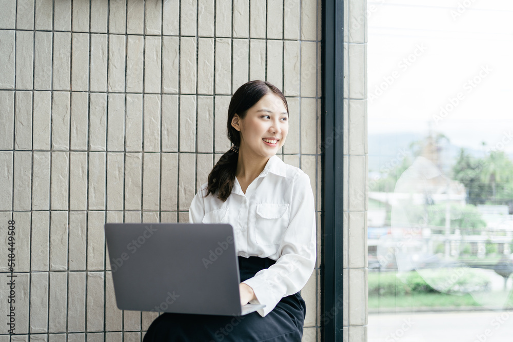 Happy young asian girl working at a coffee shop with a laptop