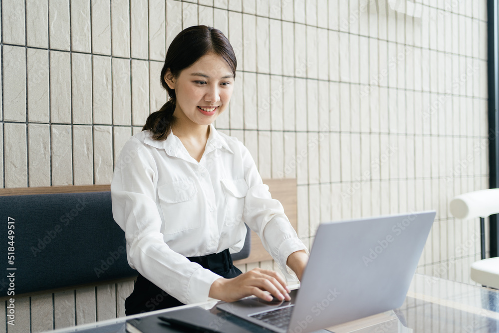 快乐的年轻亚洲女孩拿着笔记本电脑在咖啡店工作