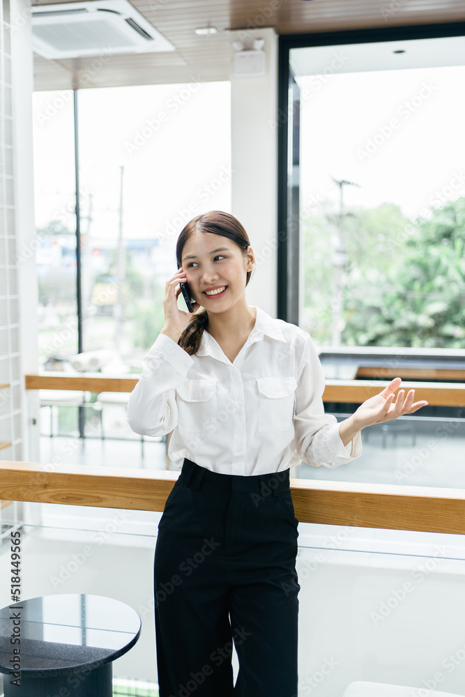 Asian businesswoman in formal suit in office happy and cheerful during using smartphone and working.