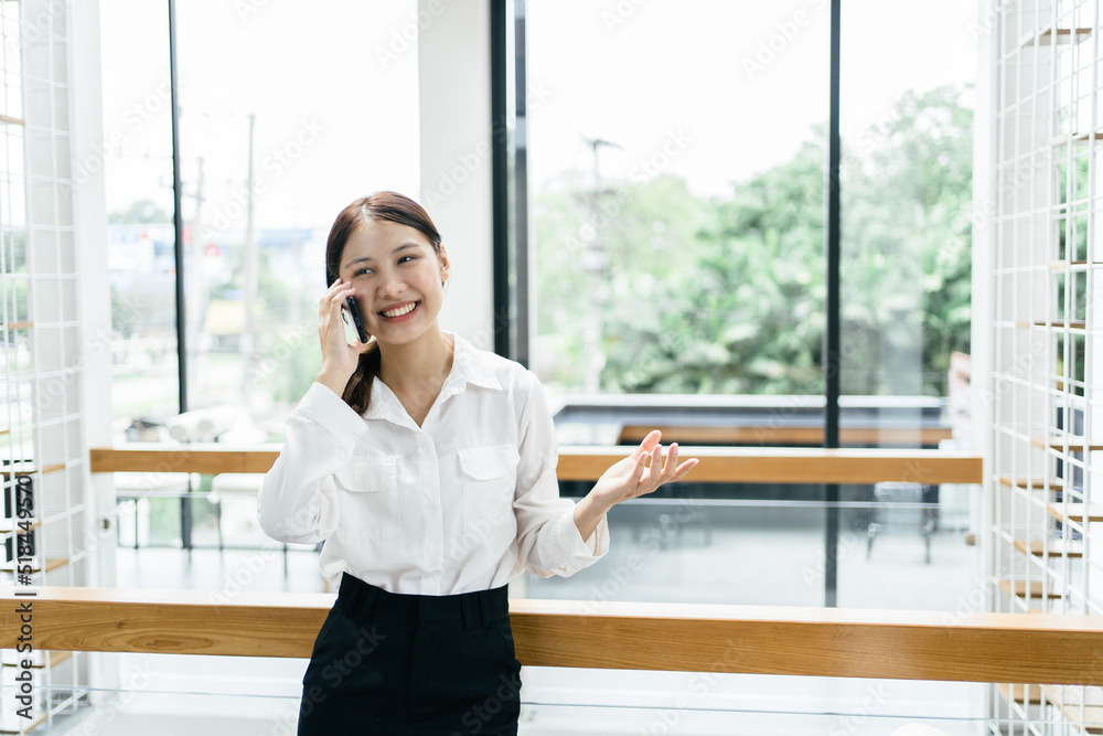 穿着正式西装在办公室的亚洲女商人在使用智能手机和工作时既快乐又愉快。