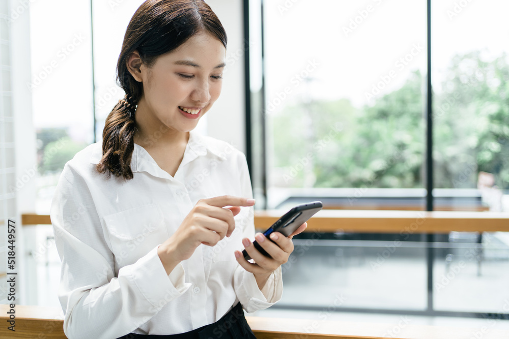 办公室里穿着正式西装的亚洲女商人在使用智能手机和工作时既快乐又愉快。