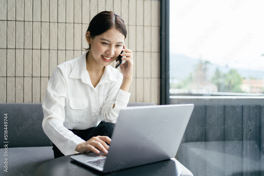 Asian businesswoman in formal suit in office happy and cheerful during using smartphone and working.