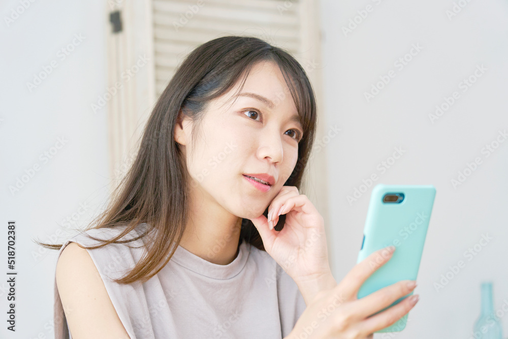 リビングでスマホを持って想像する女性