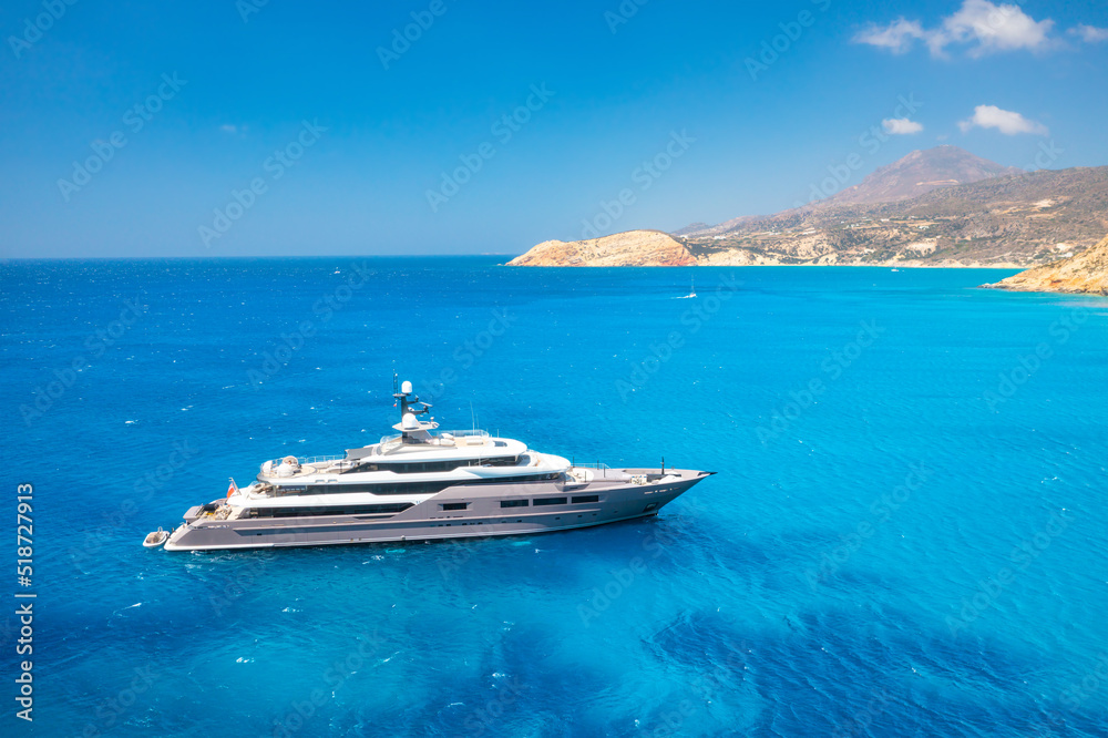 Multideck yacht in a bay with azure water. Summer holidays and trips on the ship. Aerial view of mar