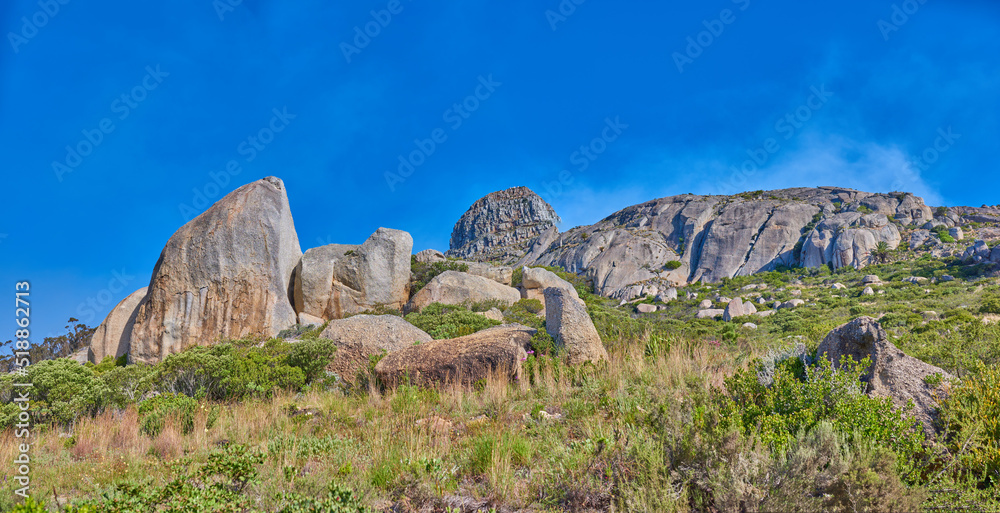 Landscape of rocky mountain with boulders against a blue sky in summer. Green field with rocks and w