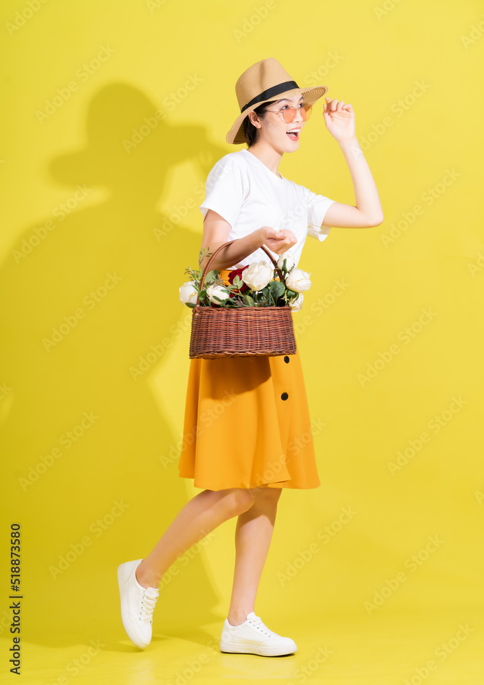 黄色背景下年轻亚洲女子手捧鲜花的全长照片