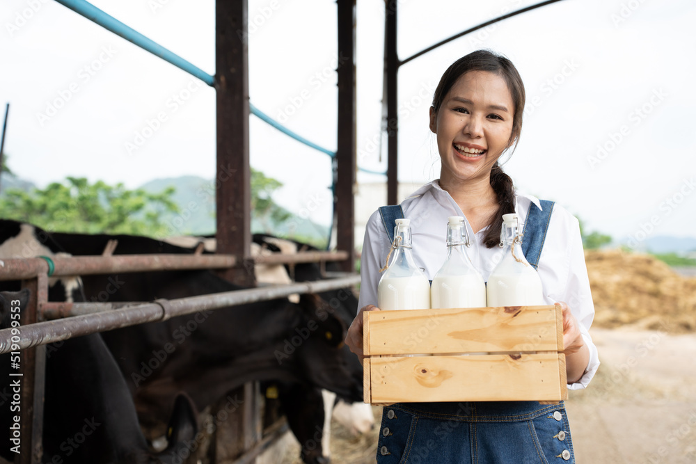 亚洲女奶农在牛棚里拿着一瓶牛奶的肖像。