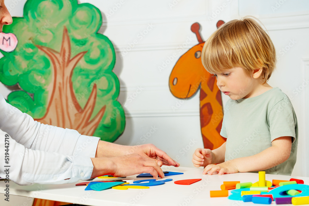 幼儿园的男孩和成年人把数字放在桌子上