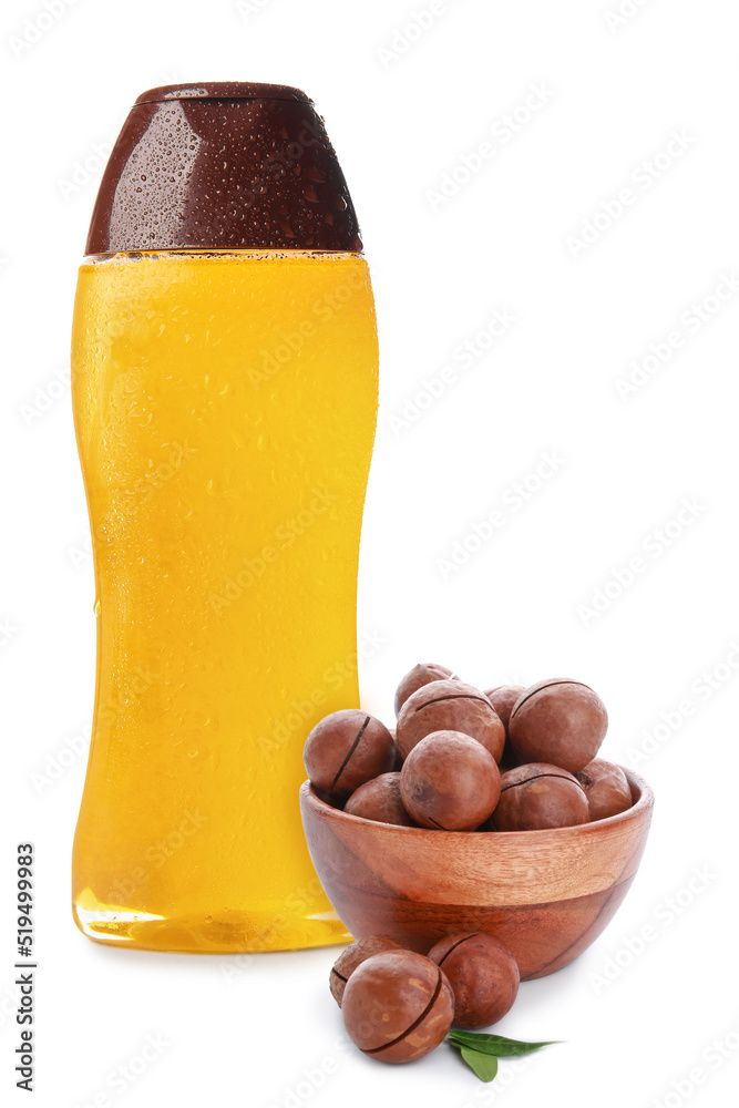 Bottle of shampoo with macadamia nuts on white background