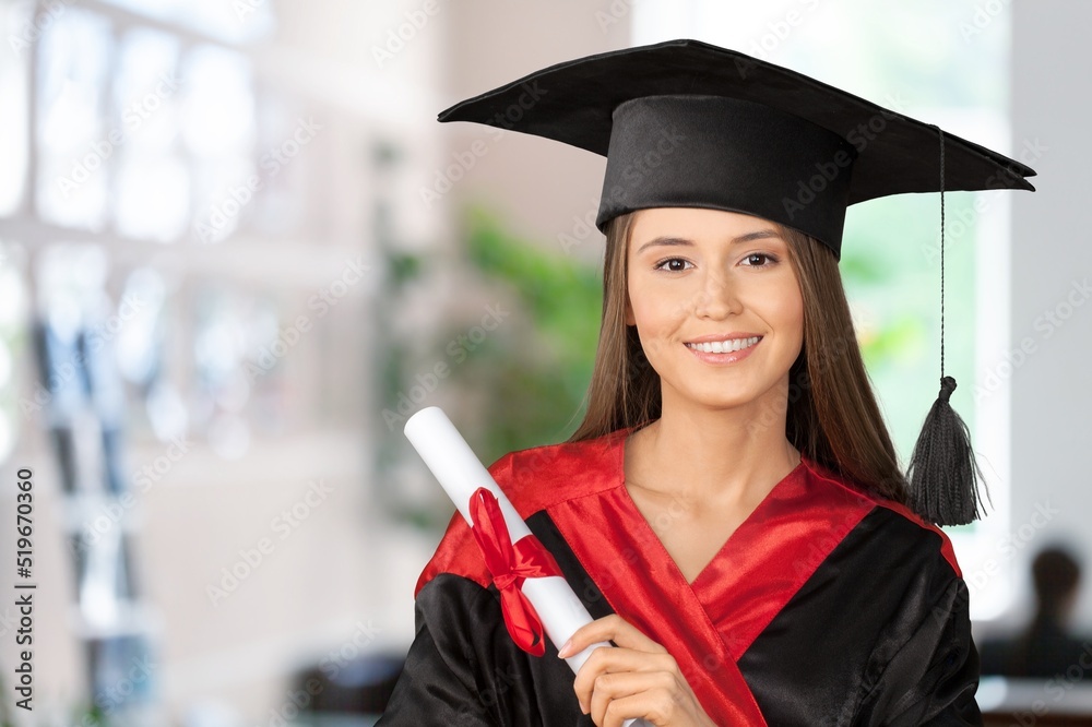 Happy young beautiful graduate female student with University degree standing and holding diploma