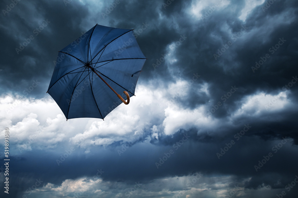 Flying blue umbrella and cloudy rainy sky closeup. Weather forecast concept