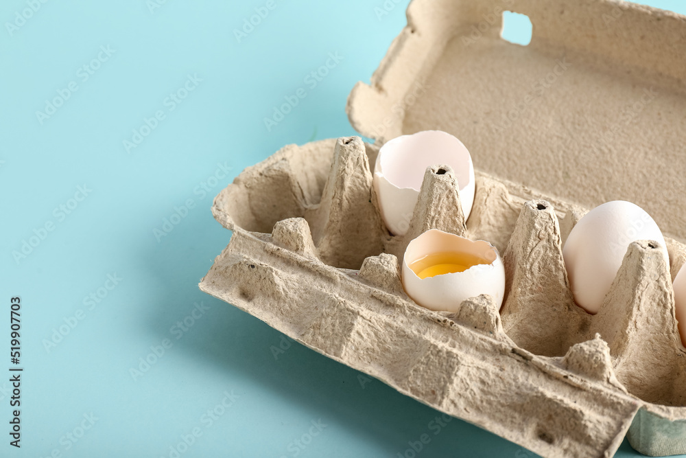 Cardboard holder with chicken eggs on color background, closeup