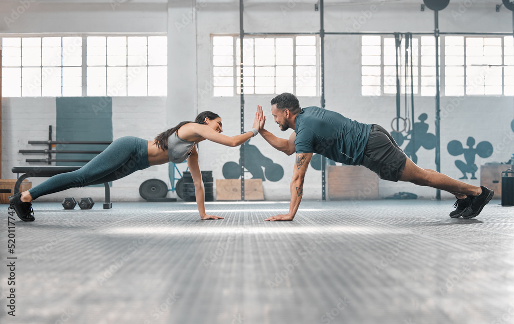 Fitness partners exercising together and doing pushups high five at the gym. Fit and active man and 