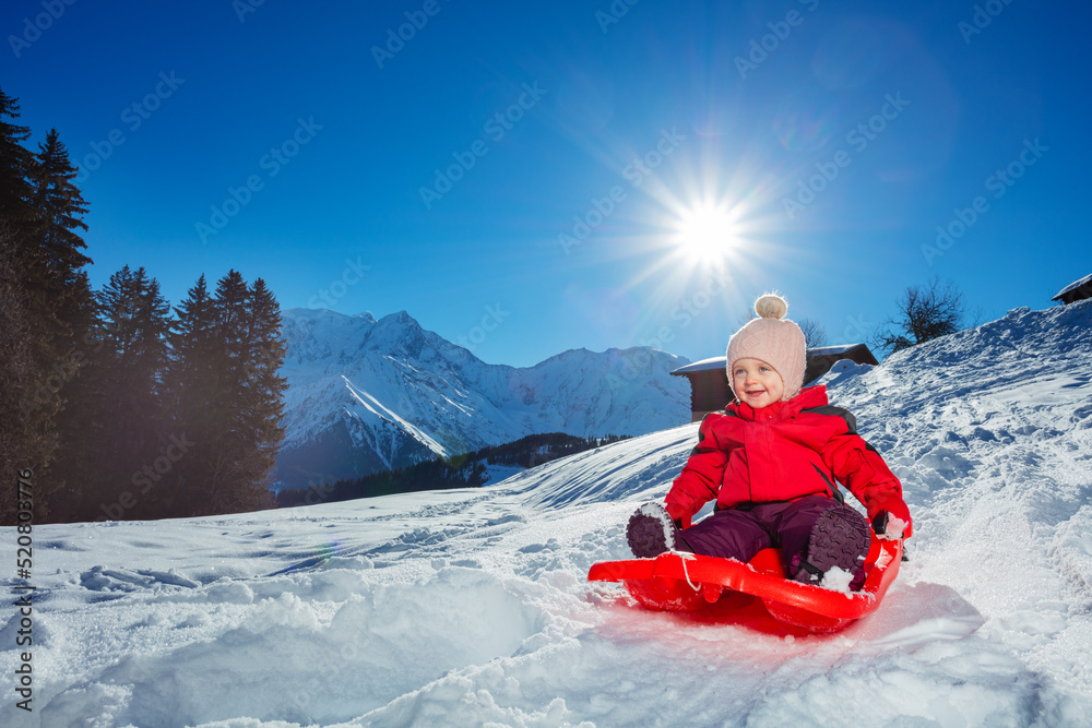 可爱的小女婴坐雪橇下坡