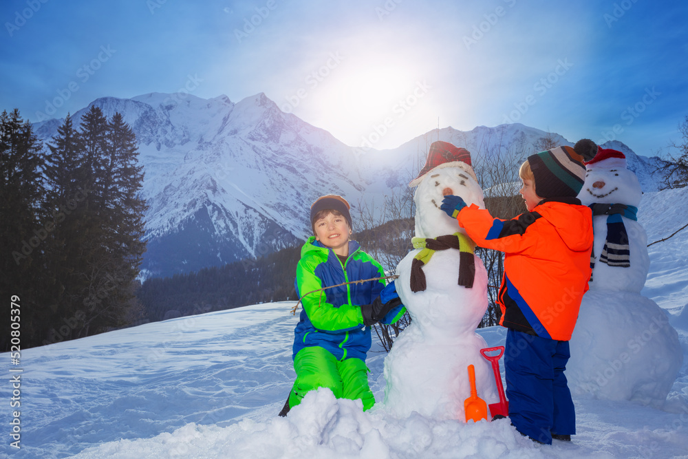 两个兄弟，男孩在外面的山上堆雪人