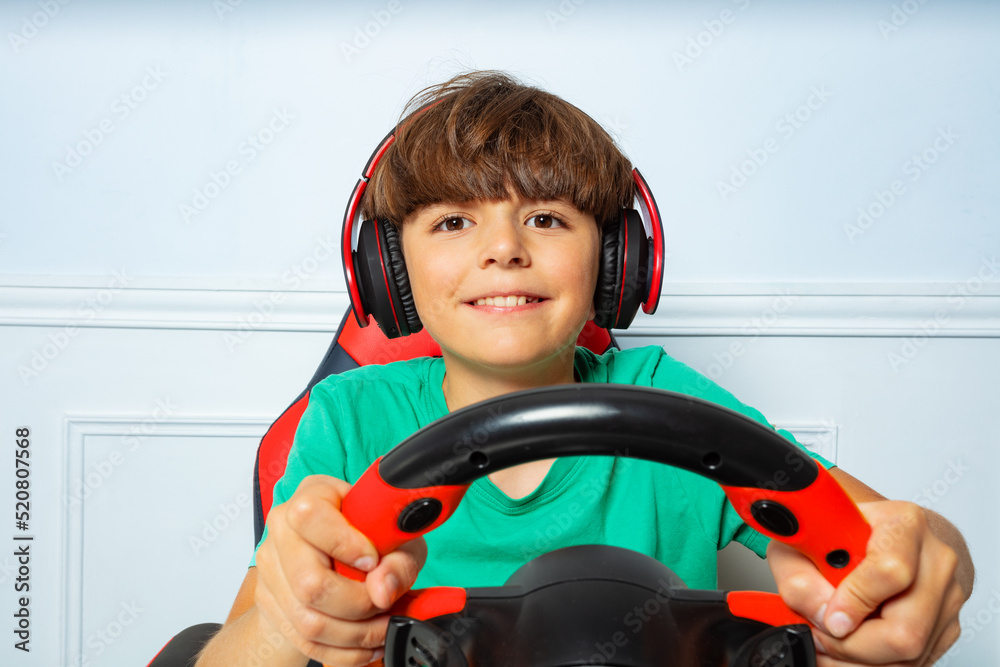 Happy boy in headphones with steering wheel play race game