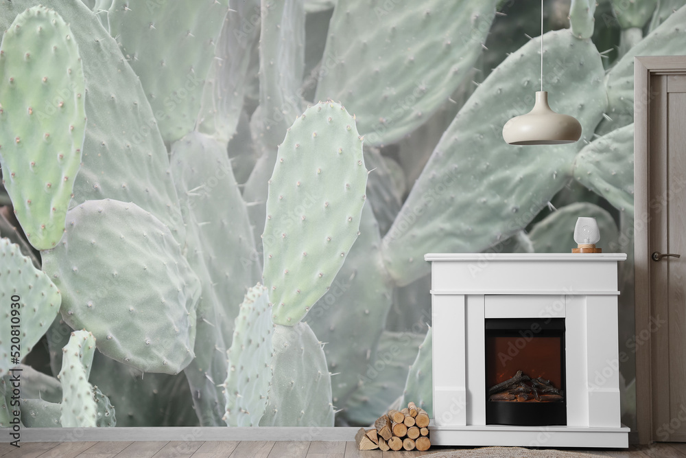 Interior of light living room with fireplace near wall with print of cacti