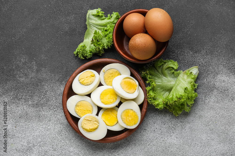 Plate with halves of boiled chicken eggs and fresh lettuce on black and white background