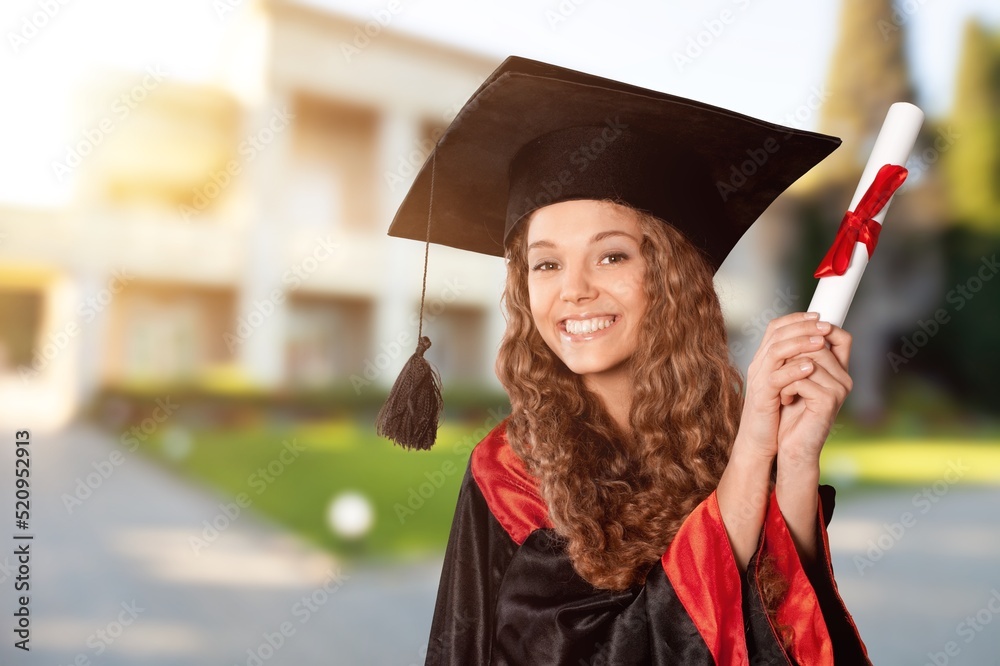 Happy young beautiful graduate female student with University degree standing and holding diploma