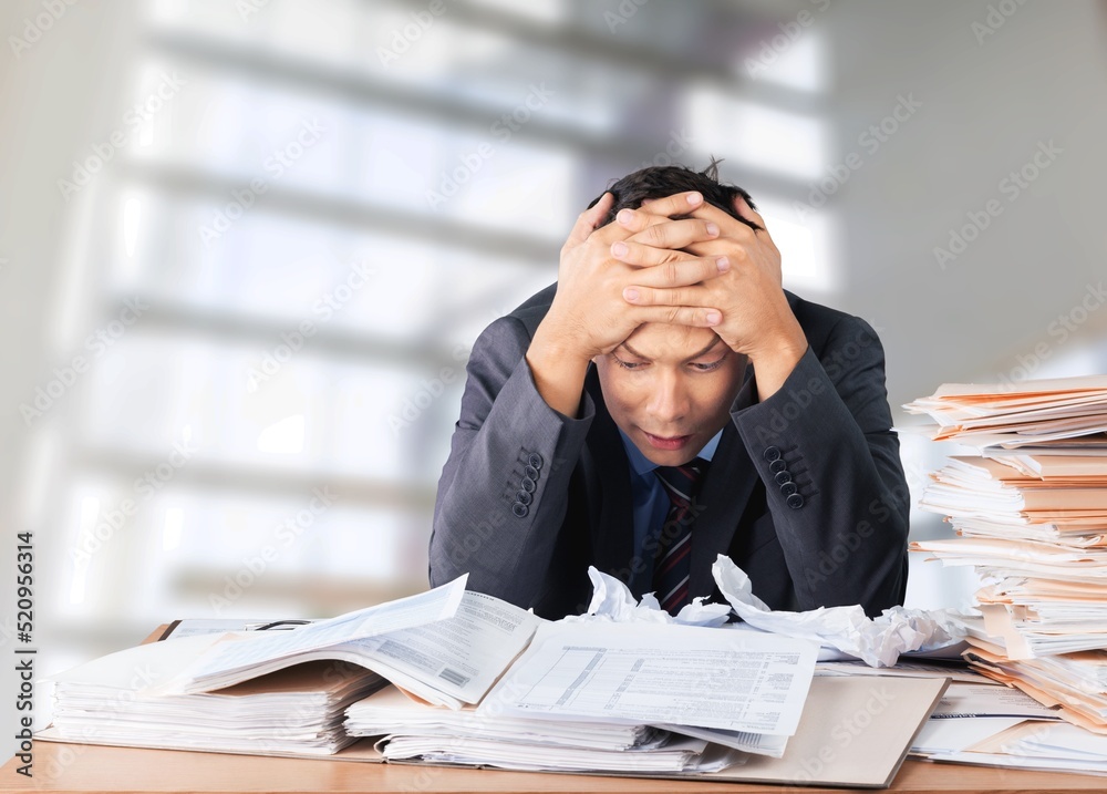 Tired exhausted man, office worker, manager or freelancer, sitting at his desk, tired of working in 