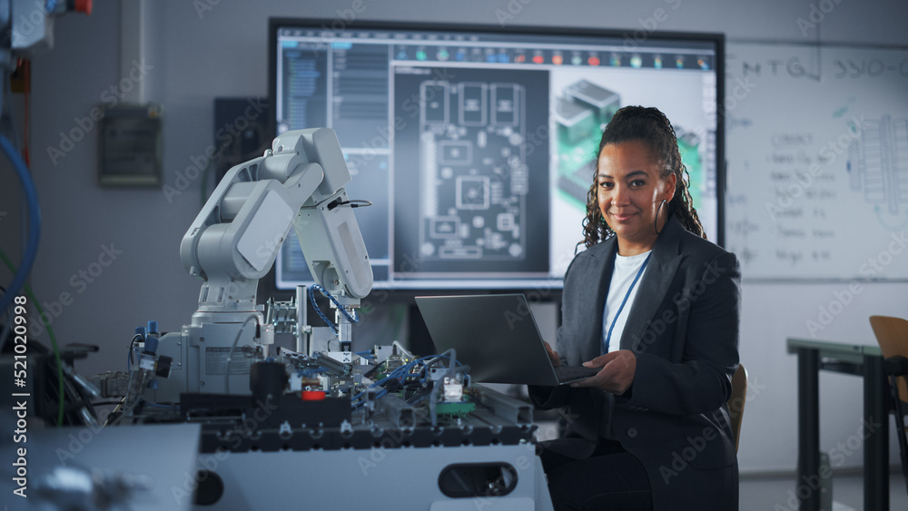 Portrait of Smiling Black Developer Using Laptop while Working with Robotic Arm in Modern University