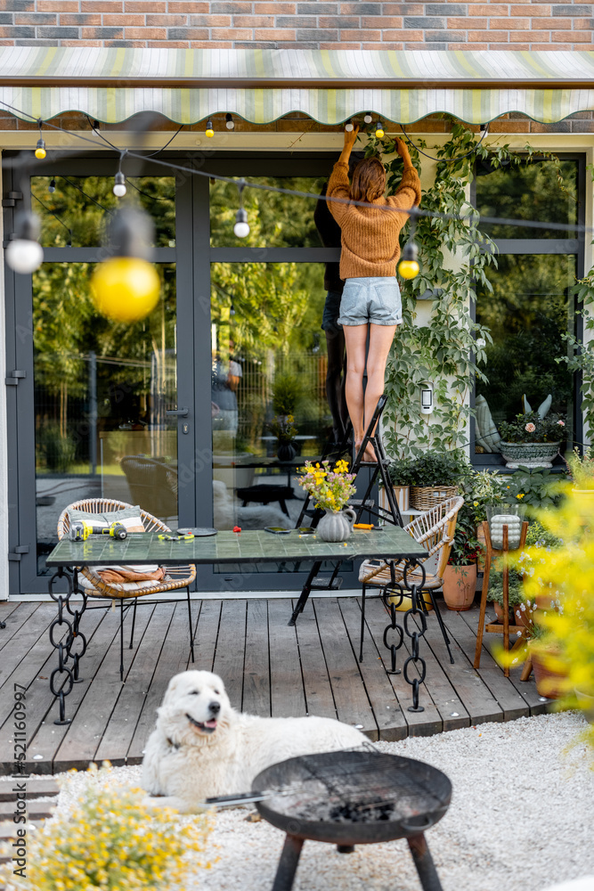 Young housewife decorates house with green ivy growing on facade, Gardening at backyard of beautiful