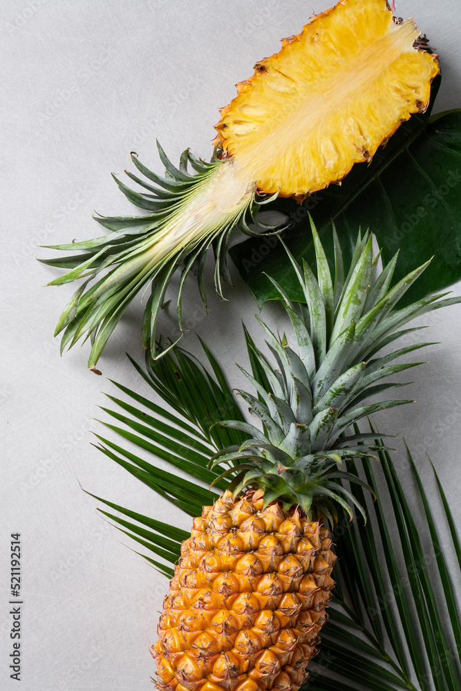 Fresh cut pineapple with tropical leaves on dark blue background.