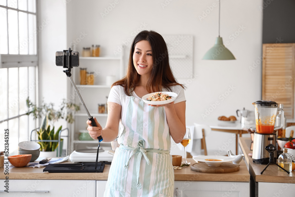 年轻的亚洲女人拿着美味的米饭在厨房自拍