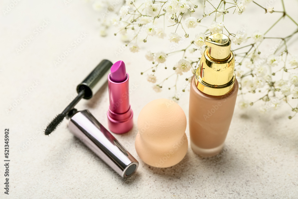 Cosmetics, makeup sponge and gypsophila flowers on light background