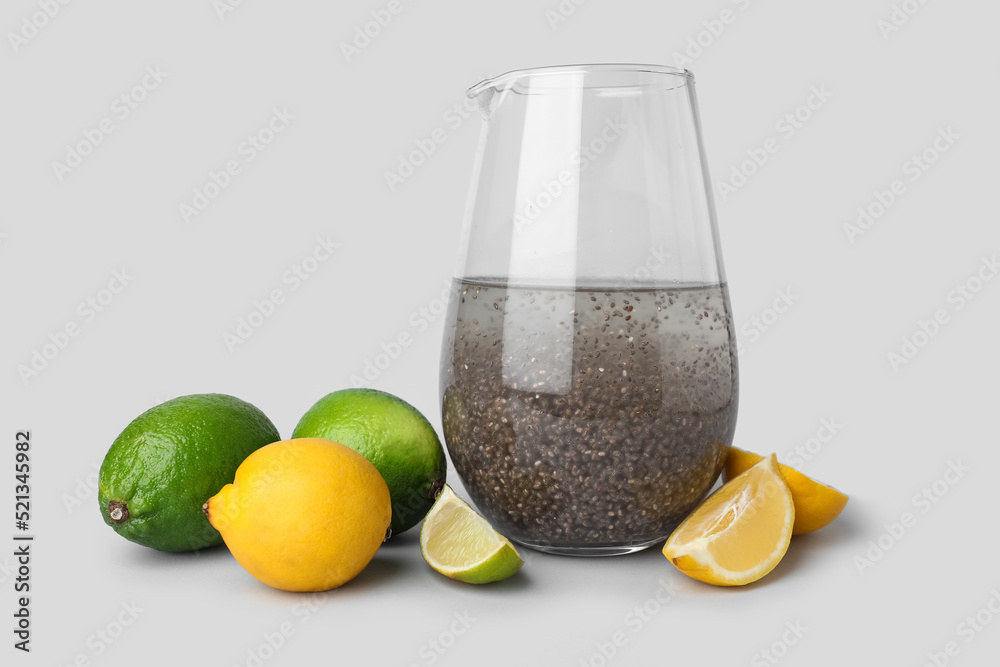 Glass of drink with chia seeds and citrus fruits on light background