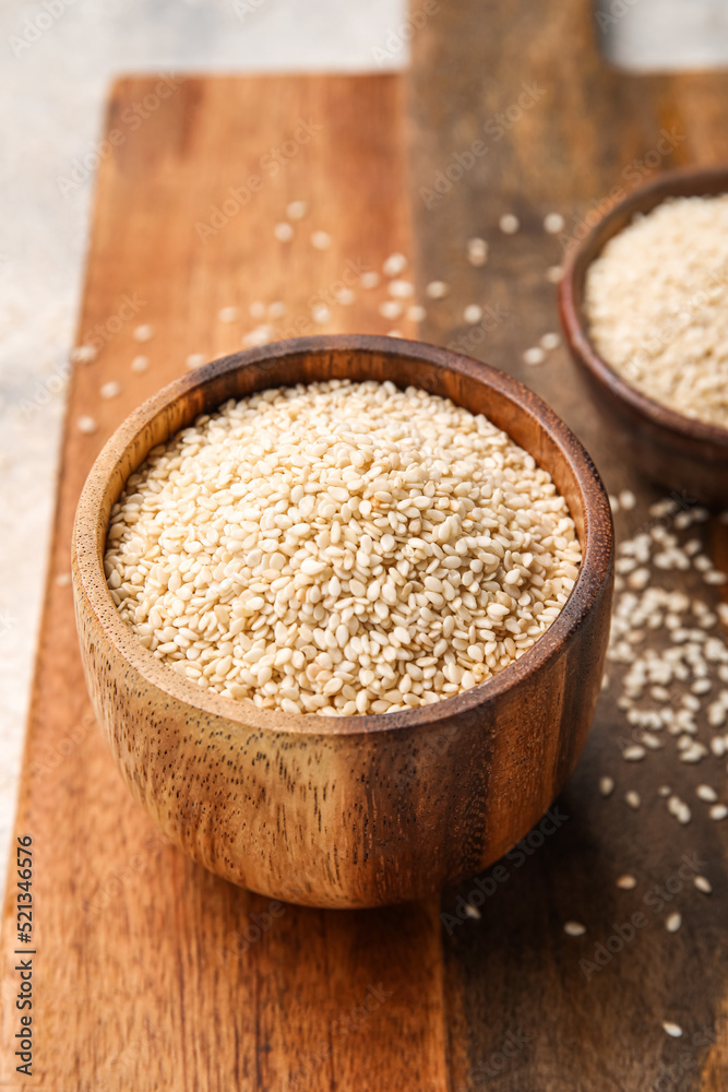 Wooden board with bowl of sesame seeds, closeup