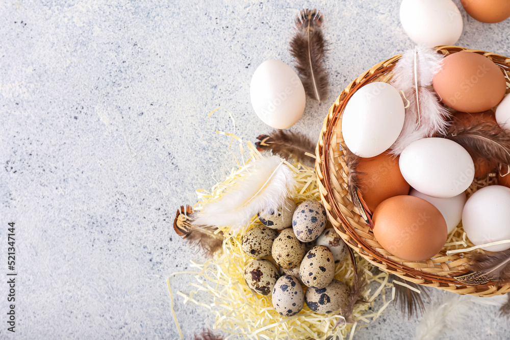 Bowl and nest with different eggs and feathers on light background