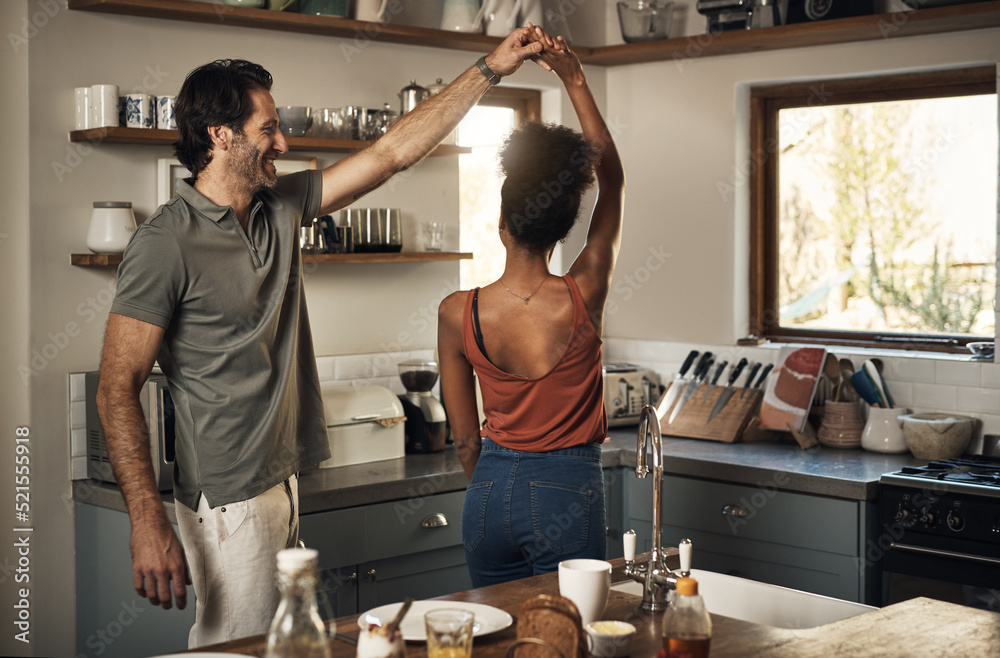 Happy, romantic and interracial couple dancing and having fun while bonding in kitchen at home. Care