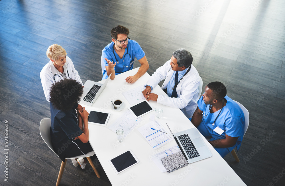 Doctors, medical professionals and workers talking in a meeting, discussing a strategy and making pl