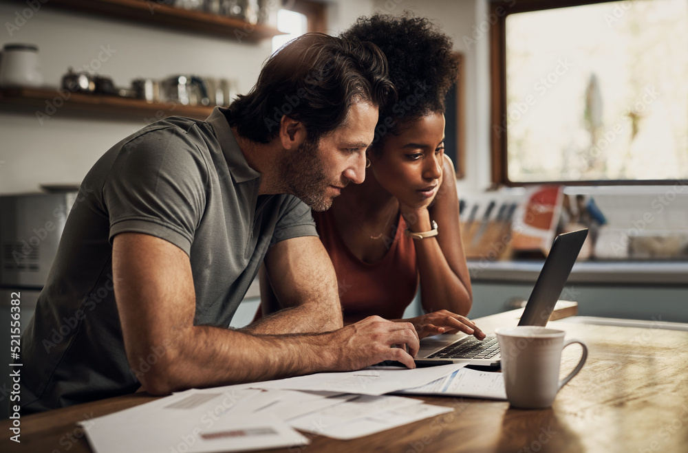 Couple with a laptop doing finance paper work, paying debt insurance loans or online ebanking togeth