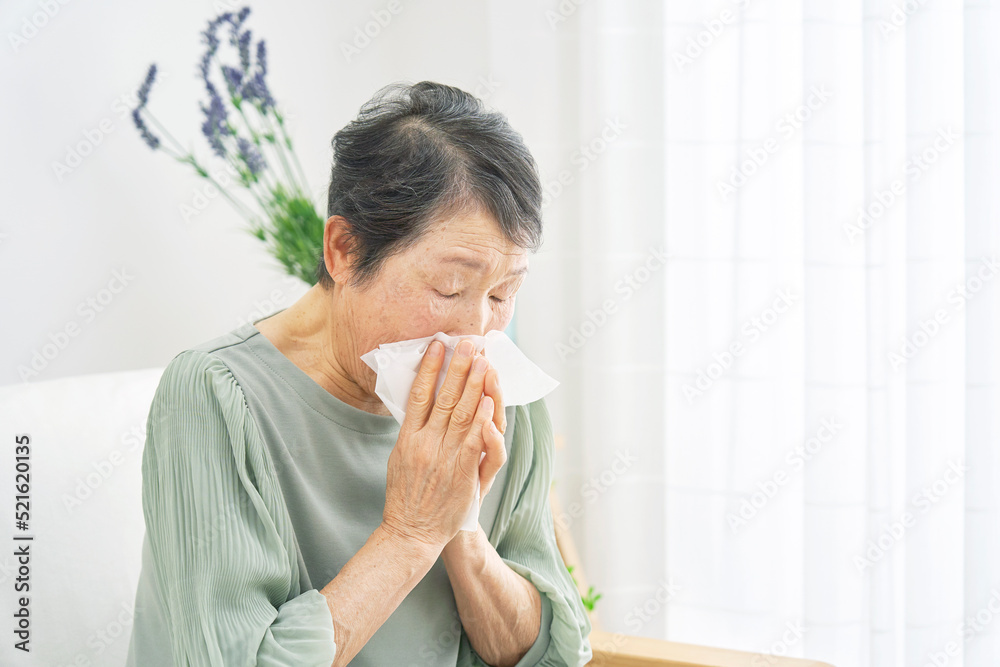 自宅で鼻をかむシニア女性