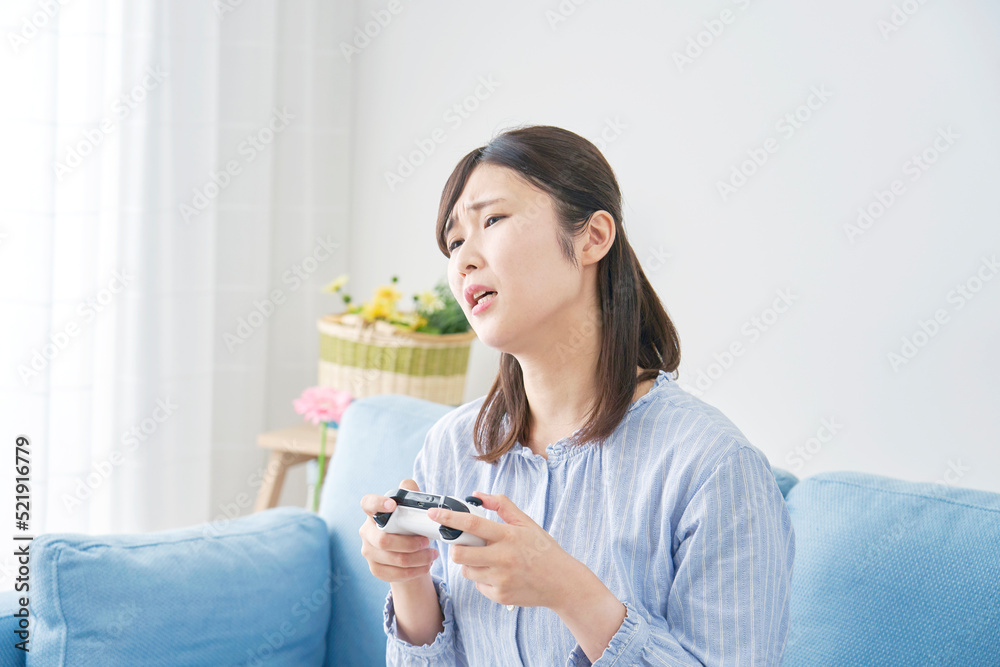 自宅で一人でテレビゲームをして落ち込む女性